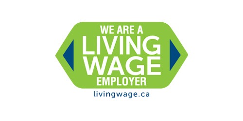 This is a logo with text stating "WE ARE A LIVING WAGE EMPLOYER" inside a green hexagon with blue borders, alongside a web address "livingwage.ca" below.