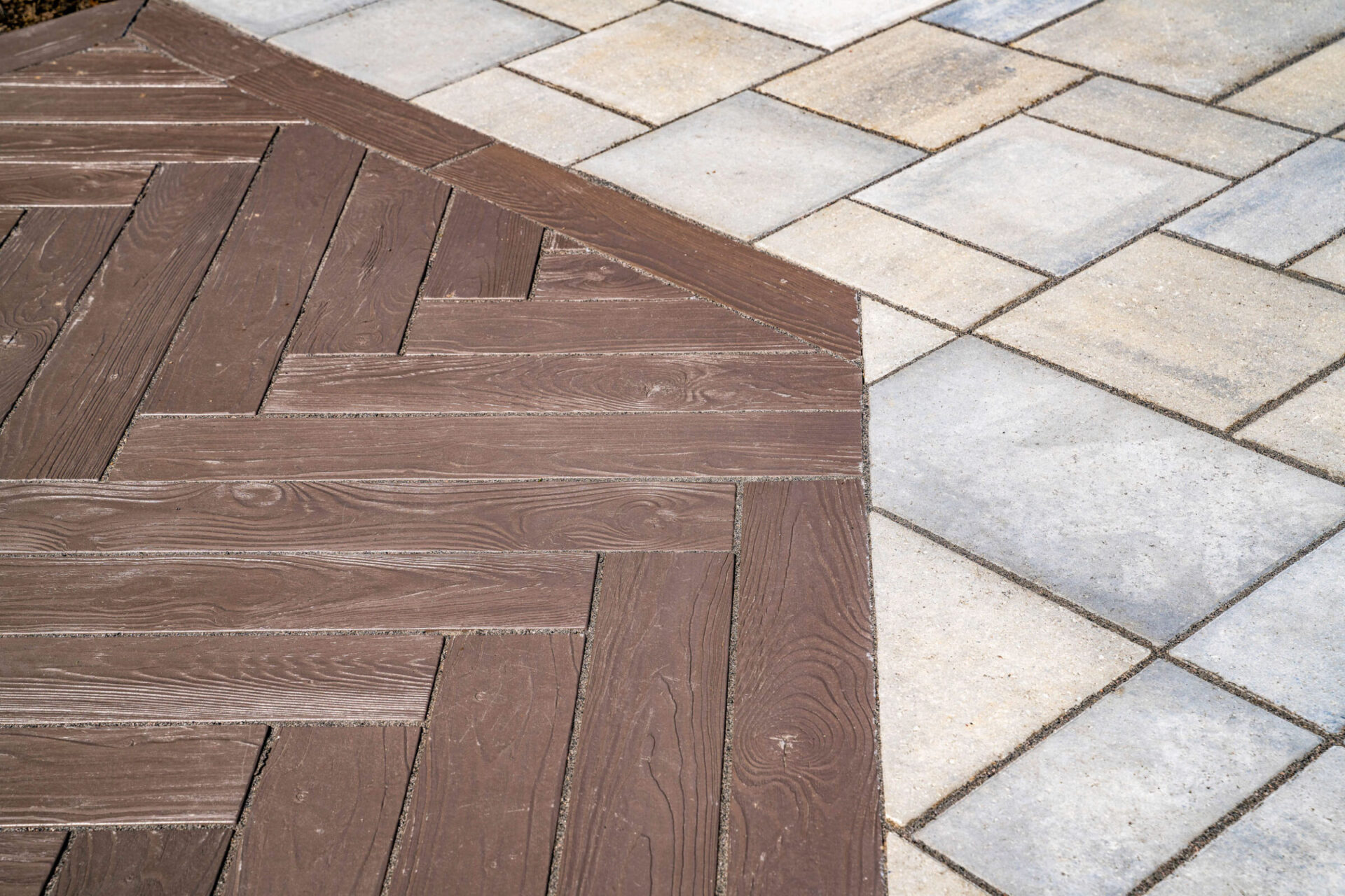 This image shows a section of outdoor flooring where wooden planks meet patterned stone tiles, creating a contrasting textural and color design.