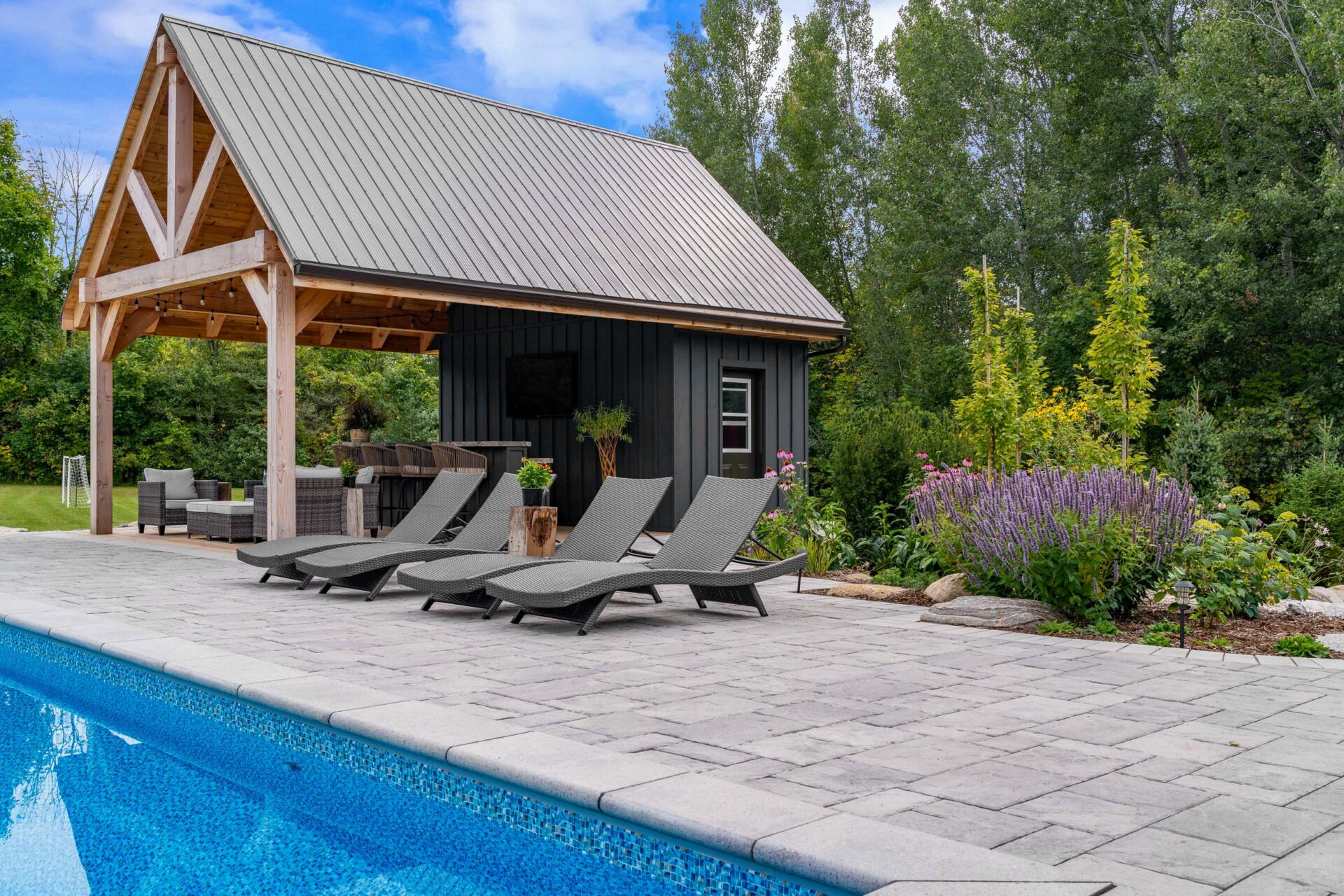 this image shows a photo of a swimming pool, lounge chairs, a pool house pergola, and garden