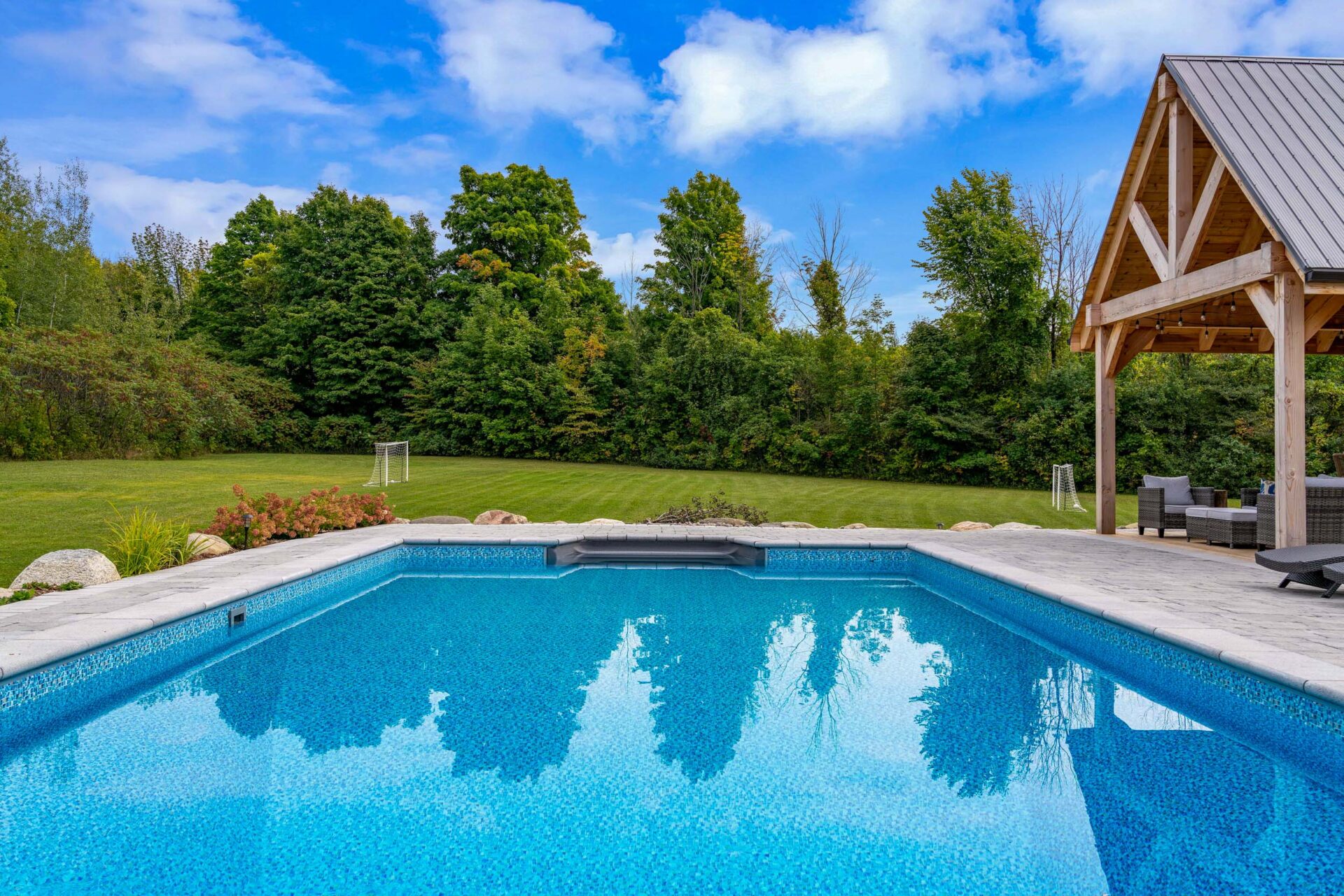 this image shows a swimming pool and a lawn cut with stripes.