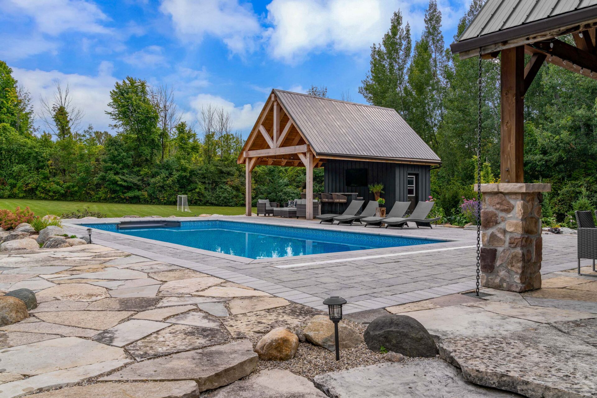 this image shows an arial photo of a swimming pool, lounge chairs, a pool house pergola, and garden