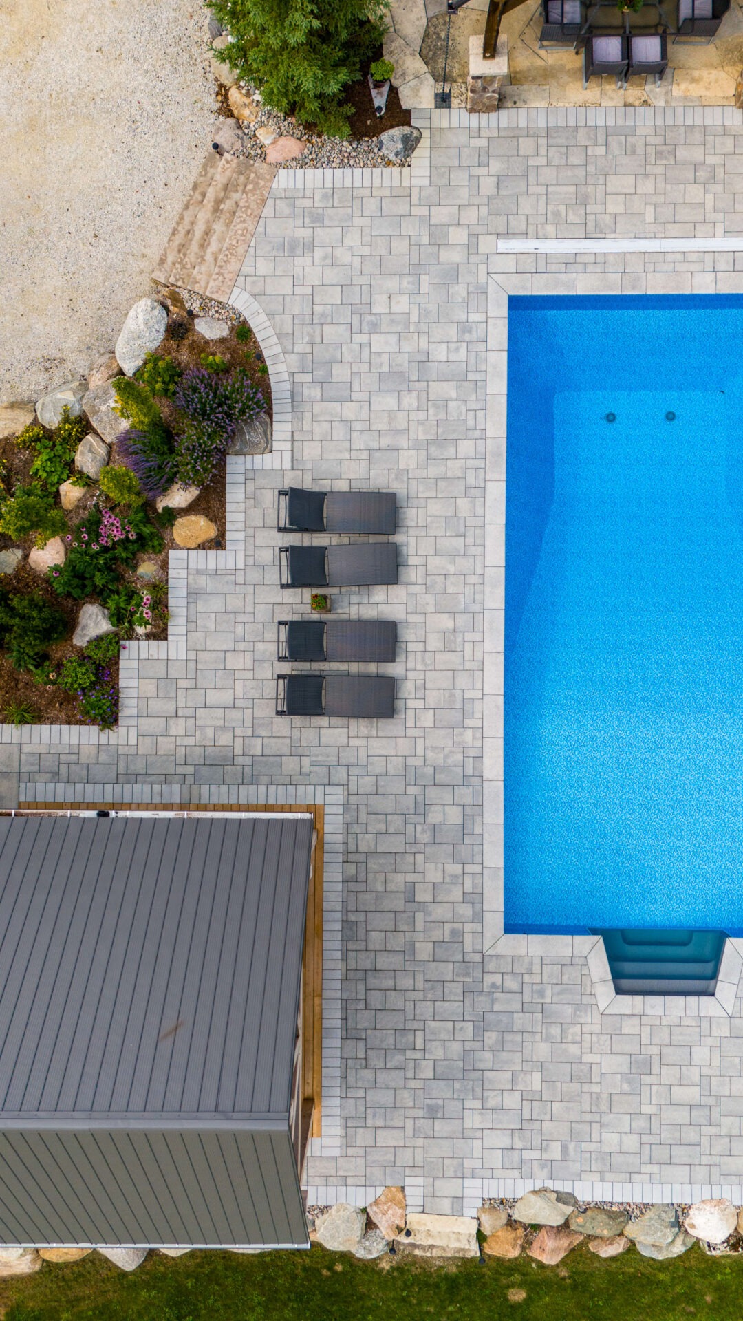 this image shows an arial photo of a swimming pool, lounge chairs, a pool house pergola, and garden