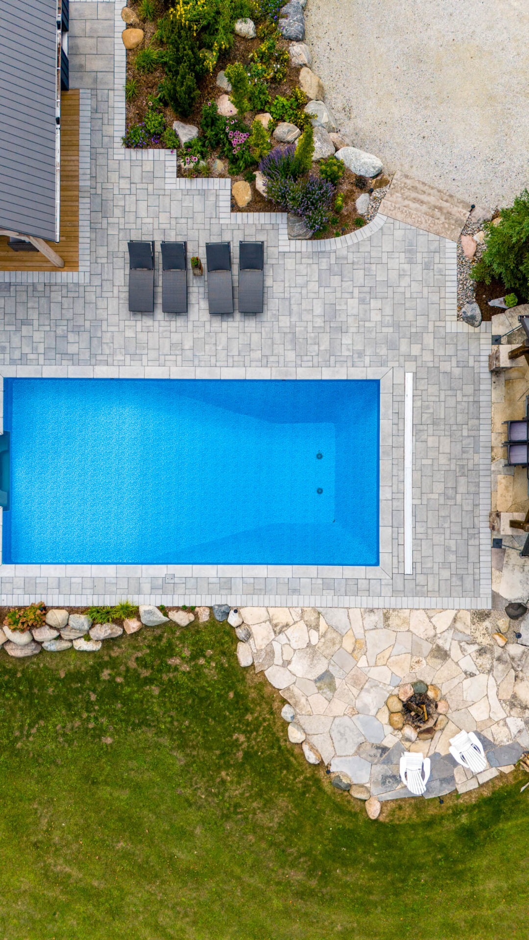 this image shows an arial photo of a swimming pool, lounge chairs, a pool house pergola, and a firepit