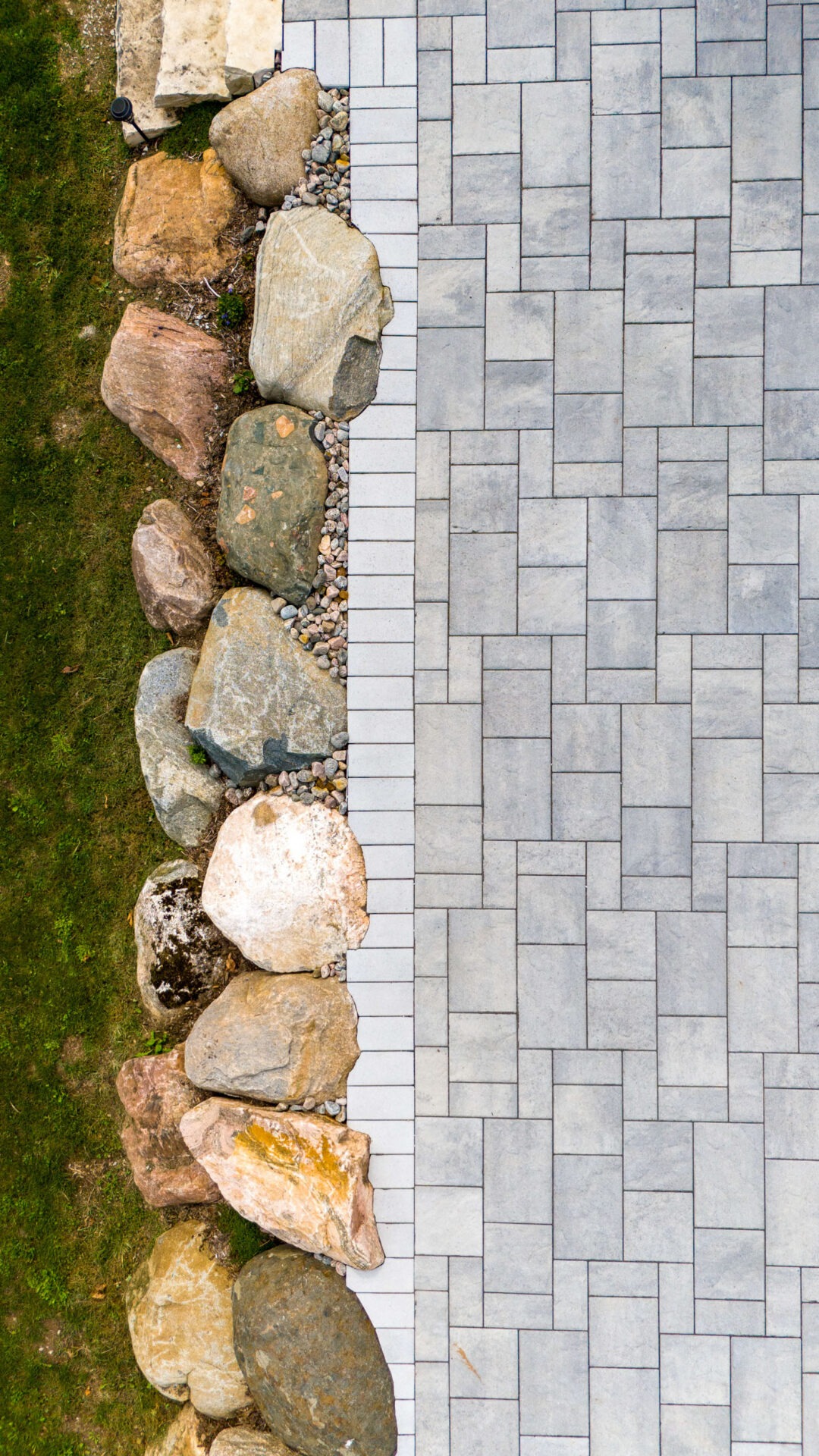 this image shows a paver patio and a boulder retaining wall with detailed cuts around the boulders