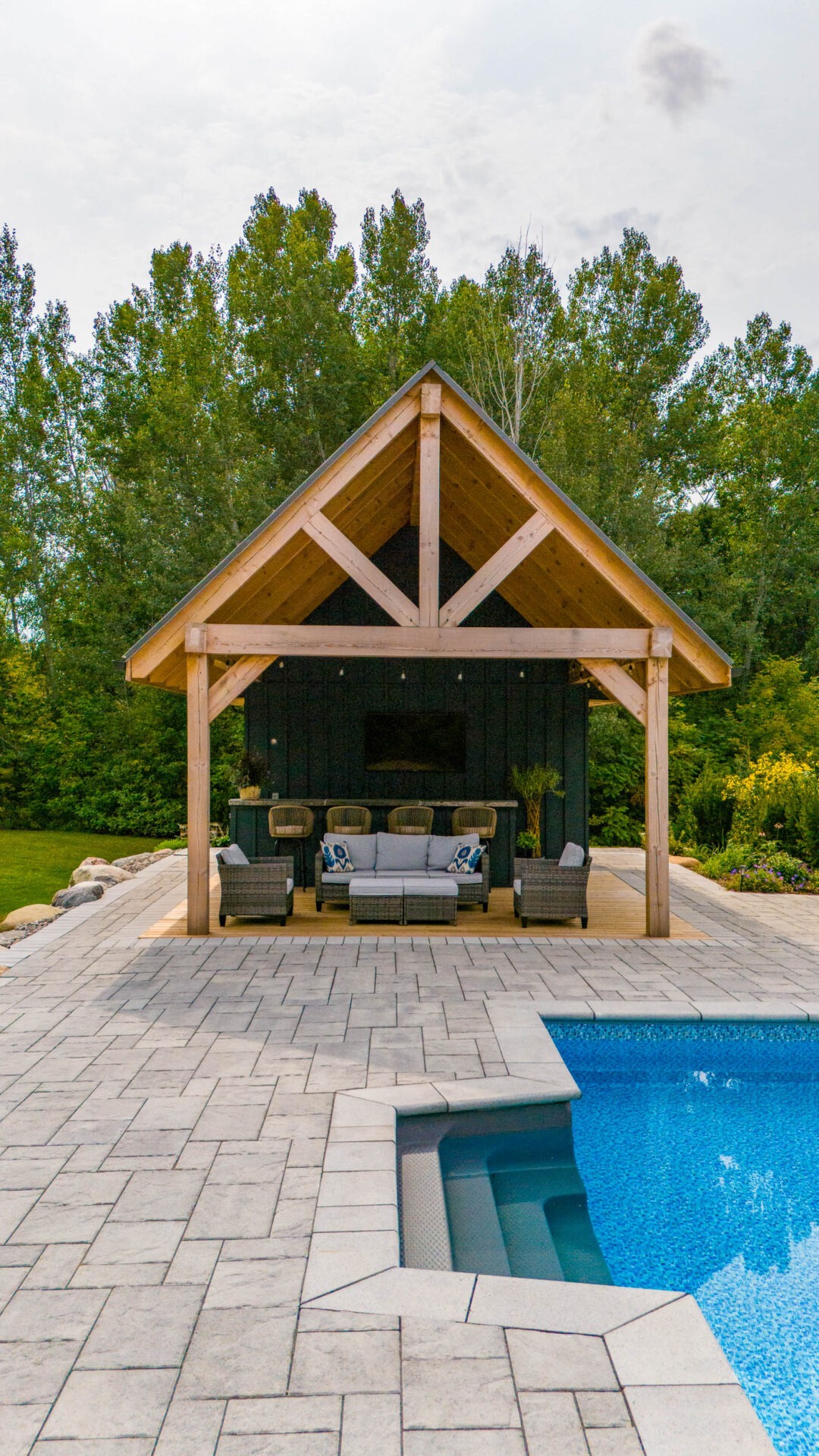 this image shows a swimming pool, outdoor living room, outdoor bar, and a pool house pergola