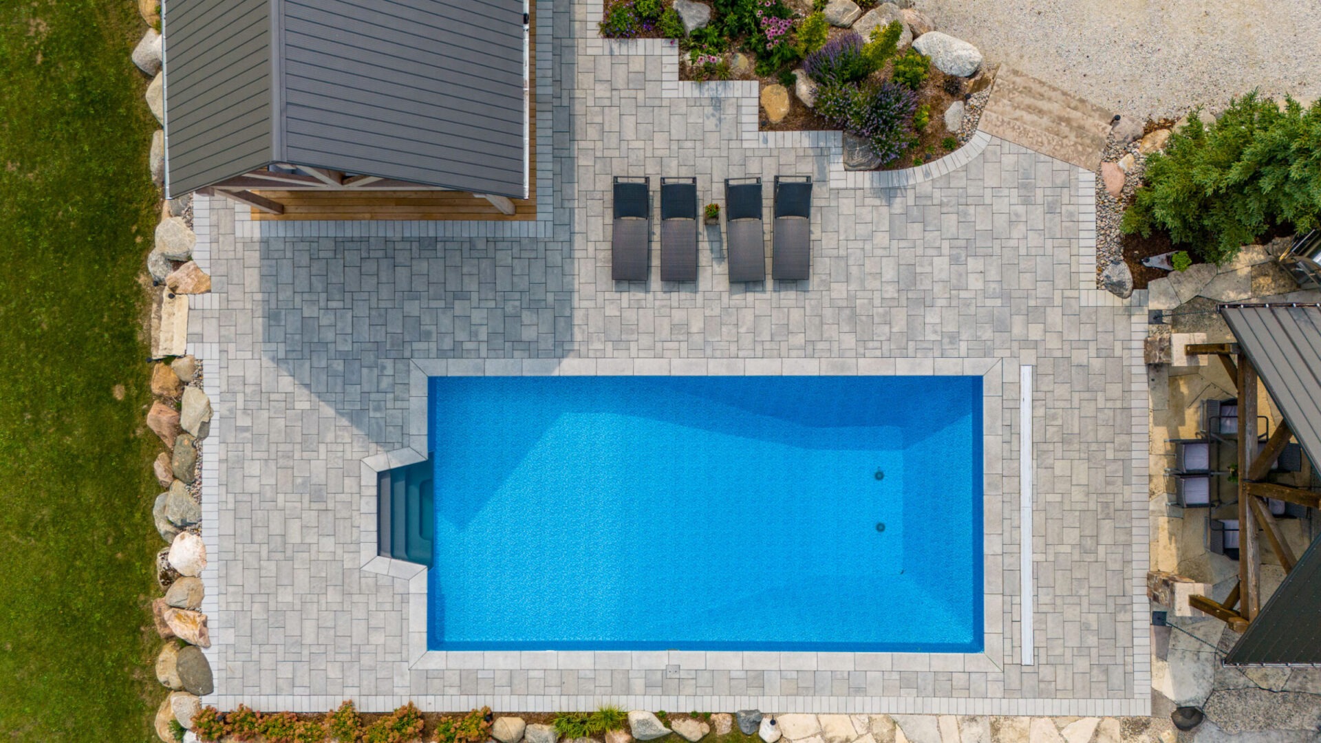 this image shows an arial photo of a swimming pool, lounge chairs, a pool house pergola, and garden