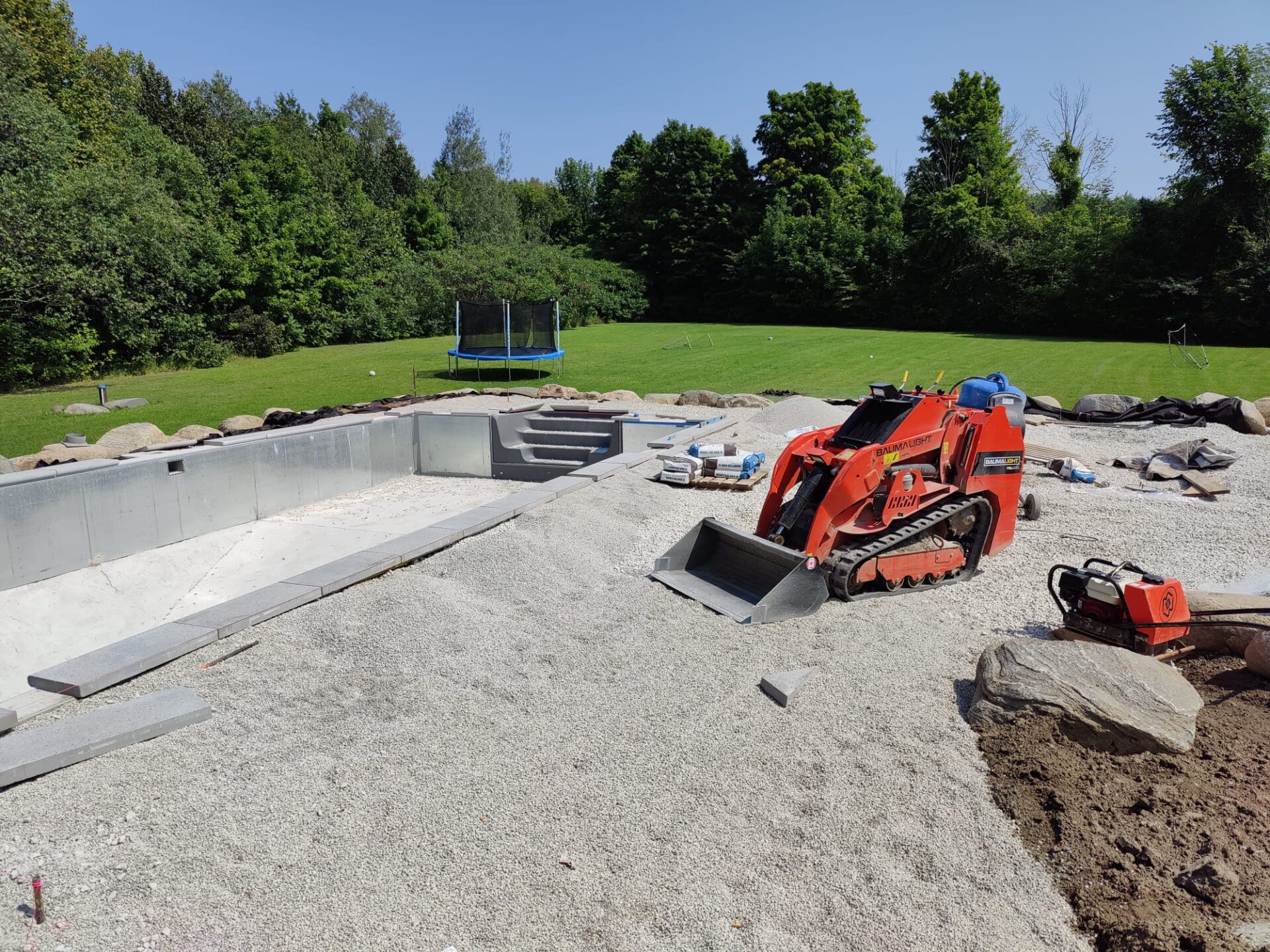 this image shows a mini skid steer laying the base of a pool deck.