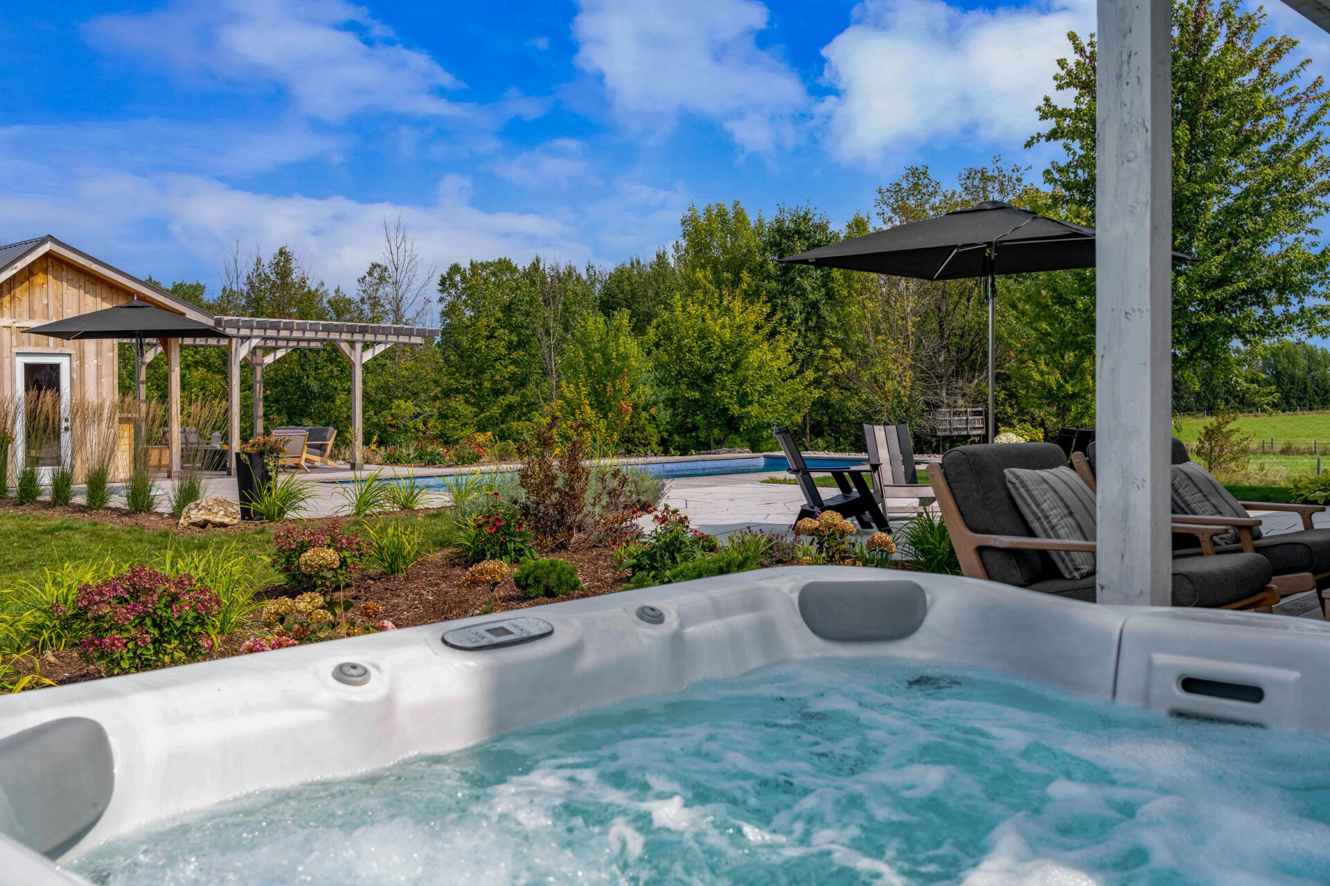 this image shows the view of a swimming pool, pollinator gardens and outdoor living spaces