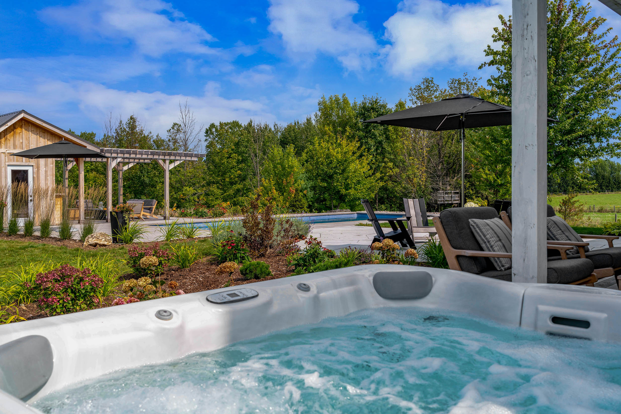this image shows the view of a swimming pool, pollinator gardens and outdoor living spaces