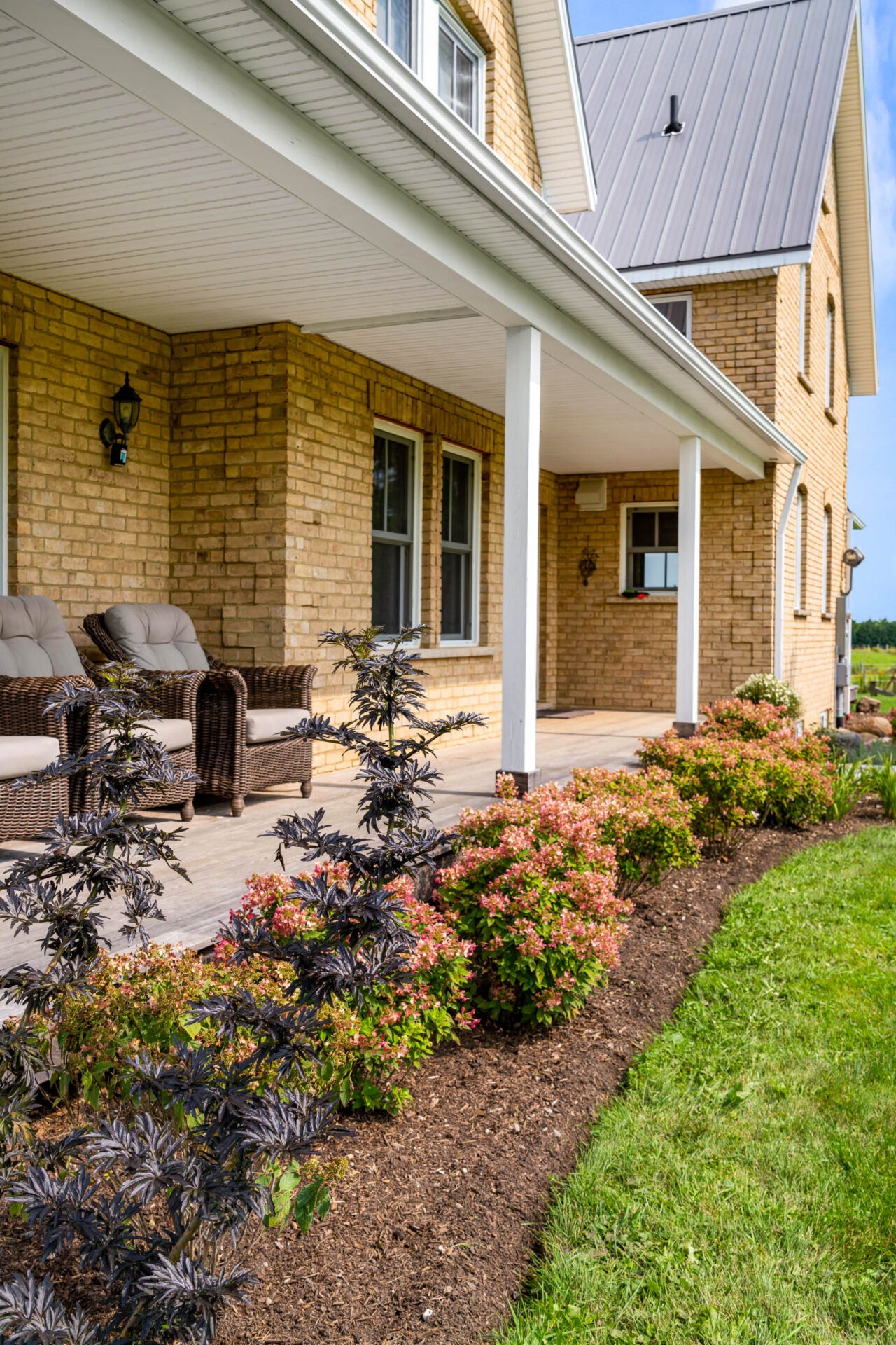 this image shows a brick farmhouse, with thermory decking and pollinator friendly garden.