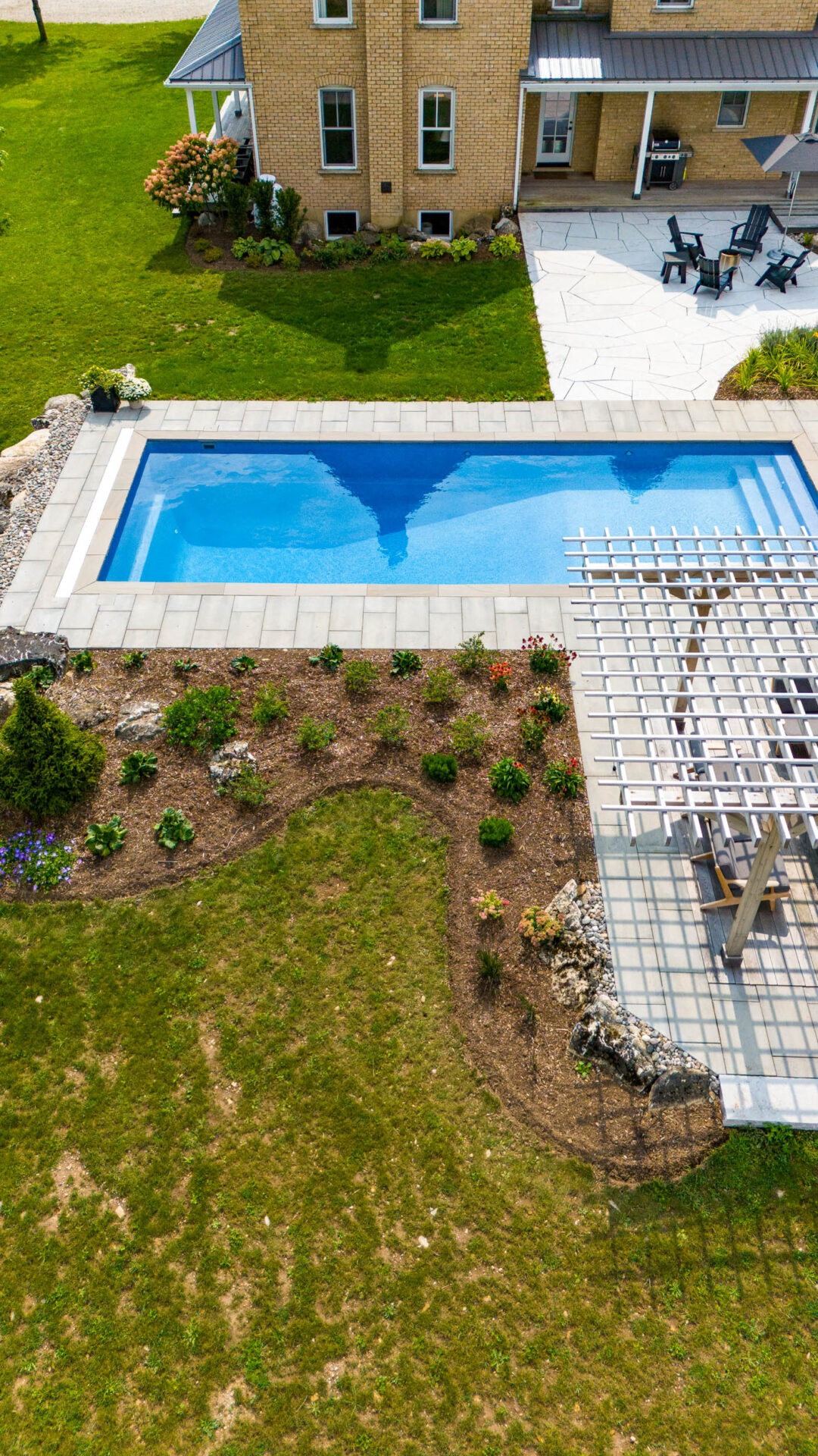 this image shows a swimming pool, pergola, pool house with sauna, outdoor living room with television and bar, pollinator gardens