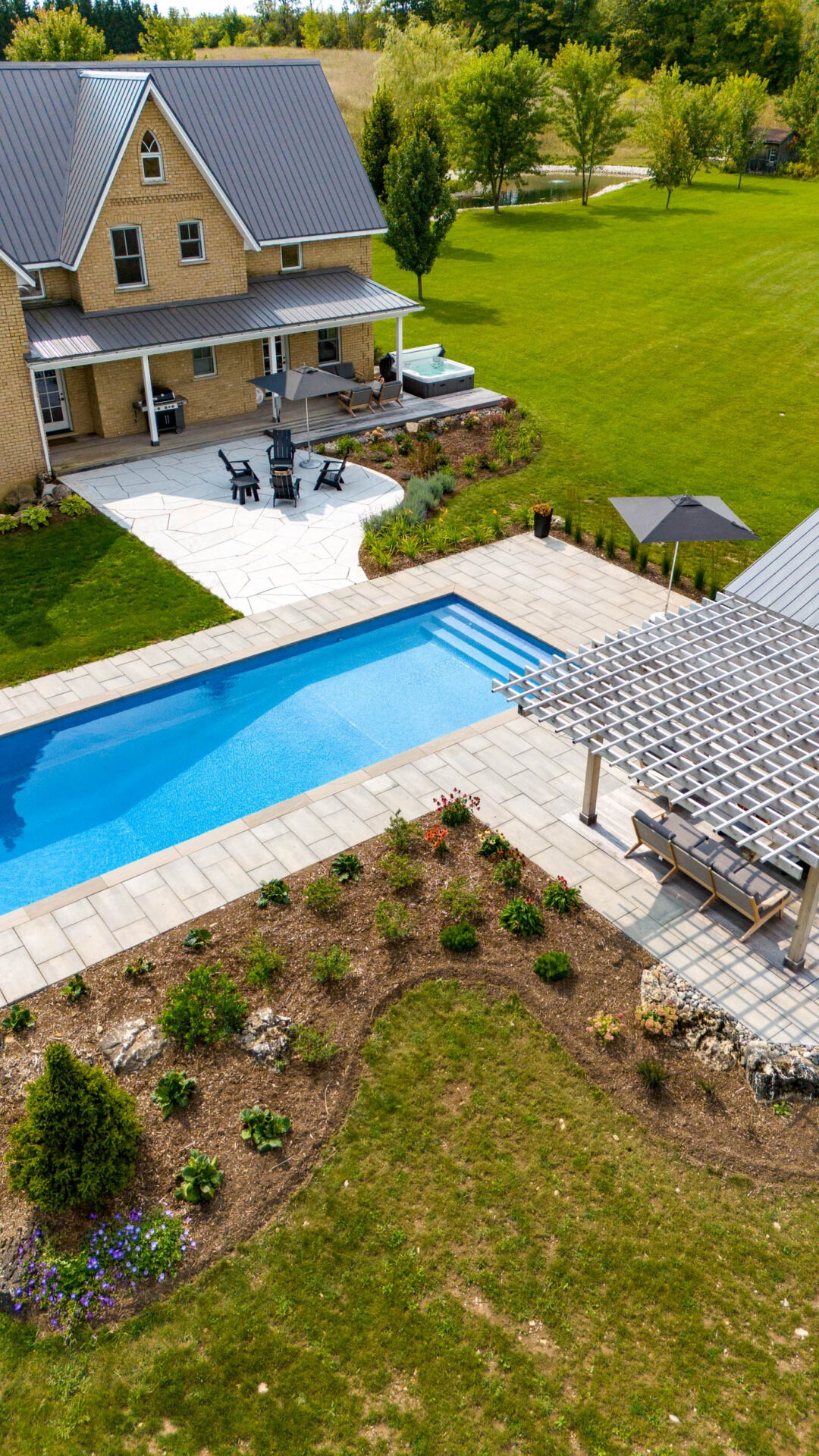 this image shows a swimming pool, pergola, pool house with sauna, outdoor living room with television and bar, pollinator gardens