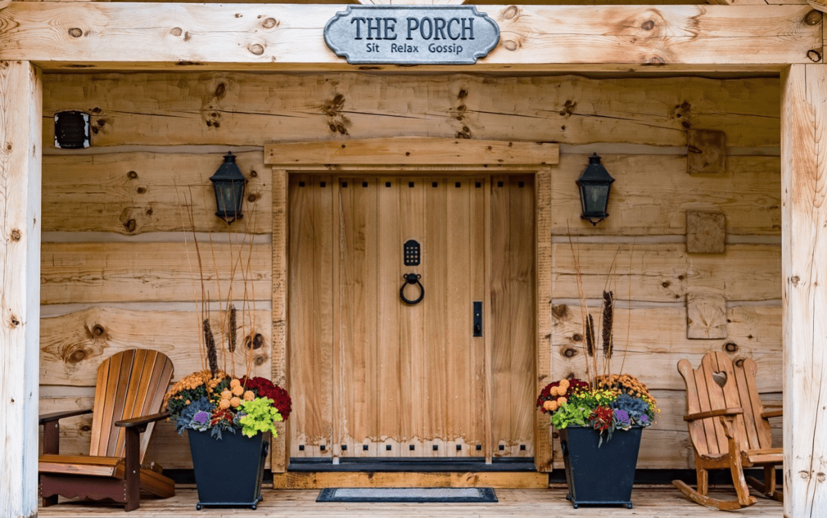A wooden porch with a rocking chair and a muskoka chair